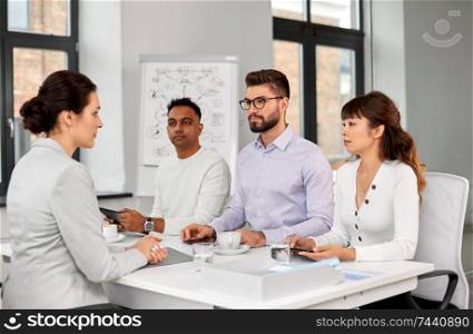 new job, hiring and employment concept - international team of recruiters having interview with female employee at office. recruiters having job interview with employee