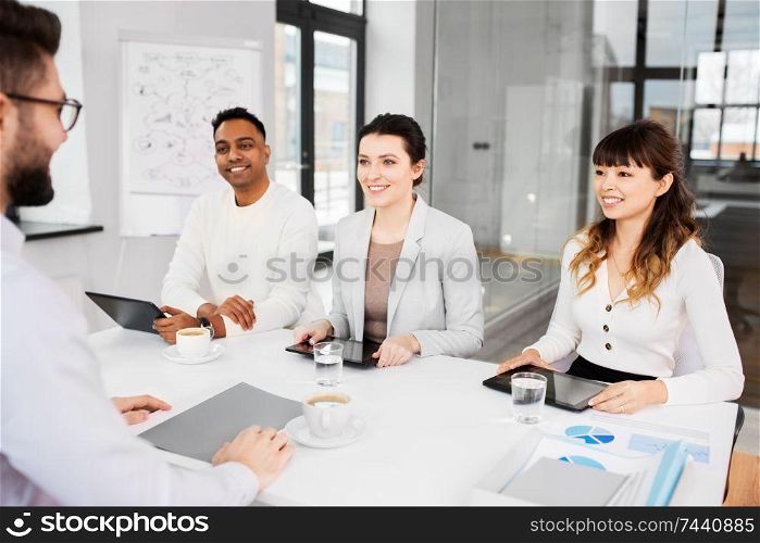 new job, hiring and employment concept - international team of recruiters with tablet computers having interview with male employee at office. recruiters having job interview with employee