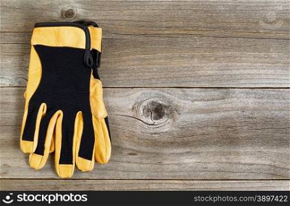 New leather and nylon utility gloves on rustic wooden boards.