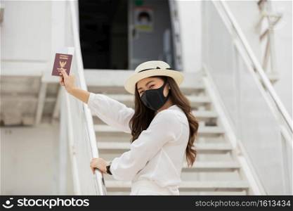 New normal of Asian young woman wearing protective mask holding passport ready to trevel at airplane,Traveling and Business during COVID-19 virus pandemic concept