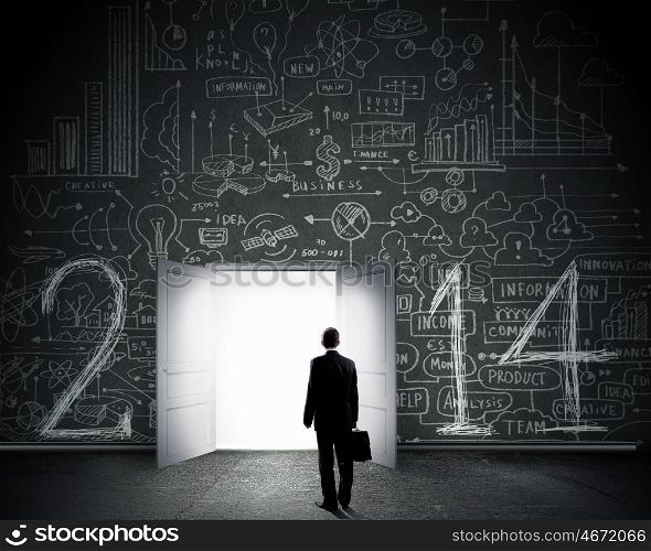 New opportunities. Rear view of businessman entering opened door in black wall