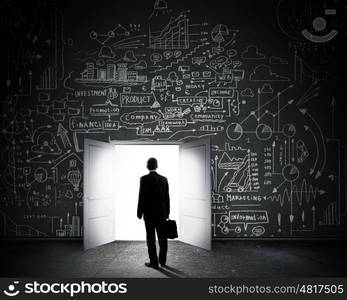 New opportunities. Rear view of businessman entering opened door in black wall