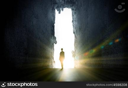 New opportunities. Rear view of businesswoman standing in light of crack in wall