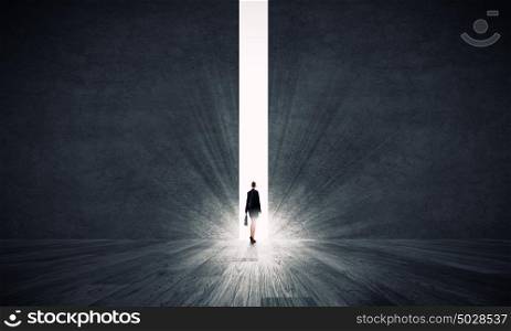 New opportunities. Rear view of businesswoman standing in light of crack in wall