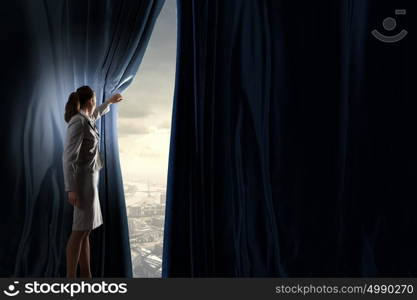 New opportunities. Young businesswoman opening stage curtain to another reality