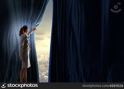 New opportunities. Young businesswoman opening stage curtain to another reality