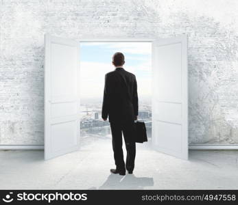 New opportunity. Image of businessman standing in front of opened door