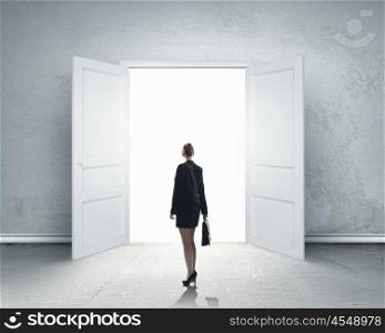 New opportunity. Image of businesswoman standing in front of opened door