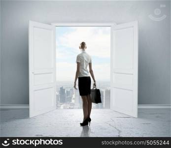 New opportunity. Image of businesswoman standing in front of opened door
