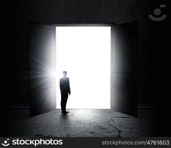 New opportunity. Rear view of businessman standing in light of opened door