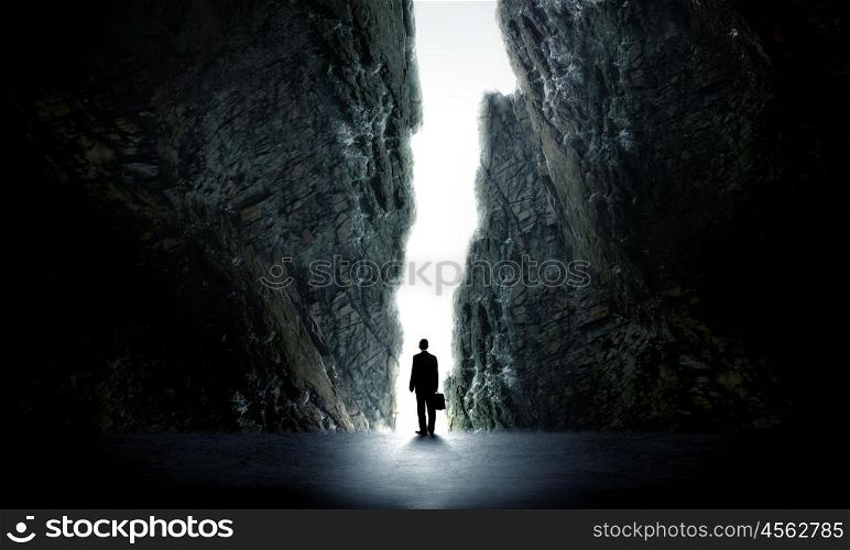 New opportunity. Rear view of businessman standing in light of way in wall