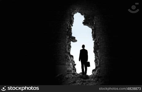 New opportunity. Rear view of businessman standing in light of way in wall