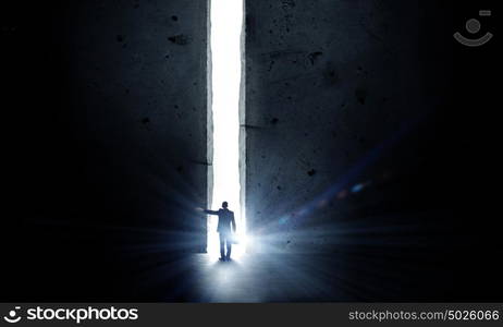 New opportunity. Rear view of businessman standing in light of way in wall