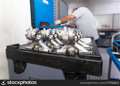 New parts of a car manufactured in the factory, blurred automotive worker at work