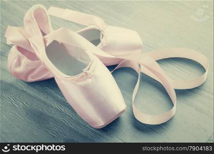 new pink ballet pointe shoes on wooden background in vintage style