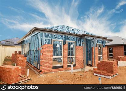 New residential construction brick home with metal framing against a blue sky