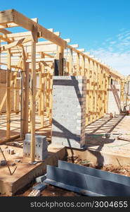 New residential construction home framing against a blue sky.