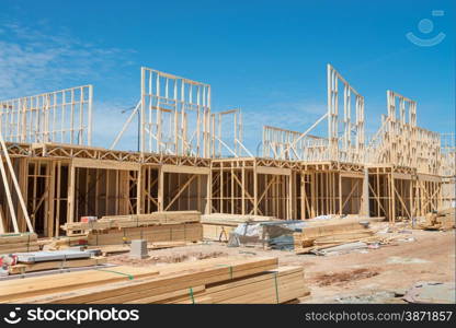 New residential construction home framing against a blue sky.