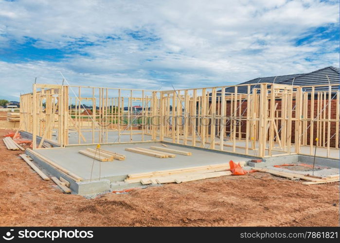 New residential construction home framing against a blue sky.