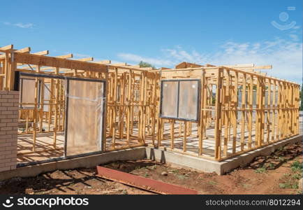 New residential construction home framing against a blue sky.