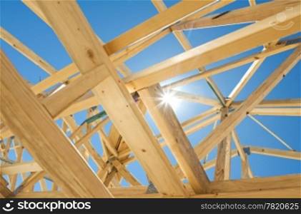 New residential construction home framing against a blue sky and sun