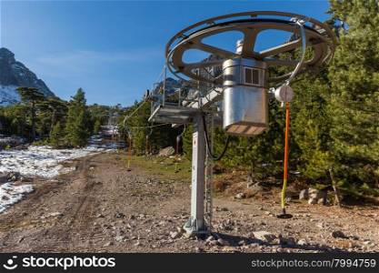 New ski lift at Haut Asco in Corsica with some snow, pine trees and mountains in the background against a deep blue sky