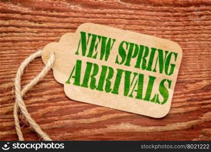 new spring arrivals - green text on a paper price tag against rustic wood