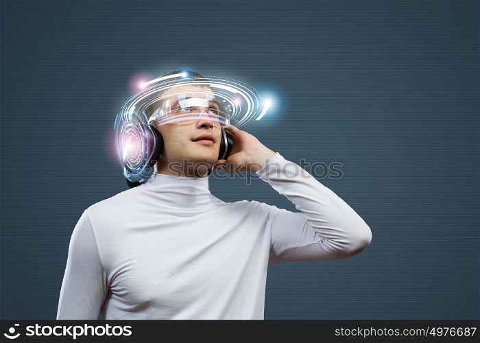 New technologies. Young handsome man against media backdrop wearing headphones