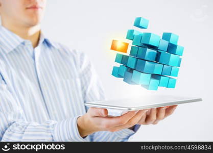 New technology integration concept. Businessman holding tablet and 3D rendering cube as symbol of problem solving