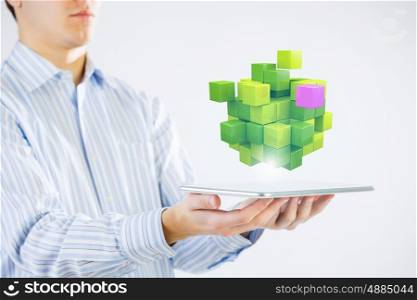 New technology integration concept. Businessman holding tablet and 3D rendering cube as symbol of problem solving
