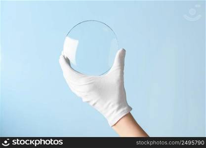 New type of glass or plastic research, hand in glove holding circle piece of transparent material