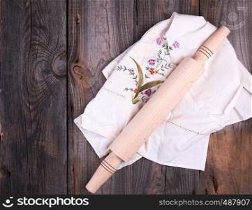 new wooden rolling pin on a textile napkin with embroidery, gray wooden background
