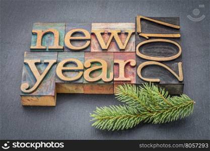 New Year 2017 greeting card - text in vintage letterpress wood type blocks on a slate stone background with a spruce twig