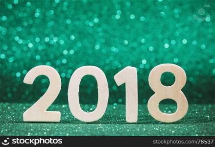 New year 2018 white wood number on green paper with glitter lights