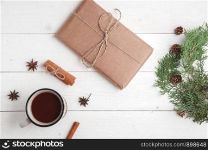 new year background. cinnamon,anise stars,fir branches,a Cup of hot chocolate and a box with a gift on a white wooden background. Flat lay. top view