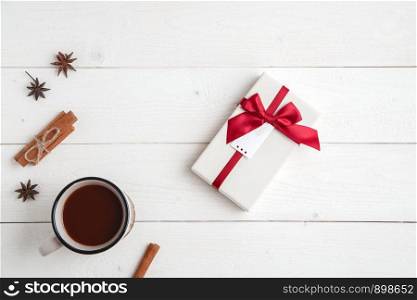 new year background. cinnamon,anise stars,fir branches,a Cup of hot chocolate and a box with a gift on a white wooden background. Flat lay. top view