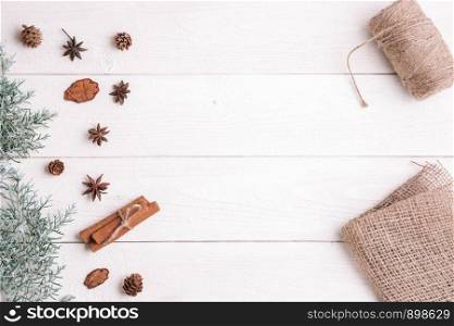 new year background. flatlay. cinnamon,fir branches on white wooden background,fabric and threads for gift packaging