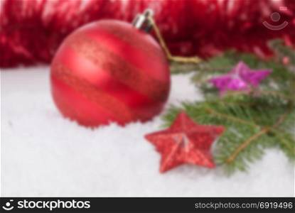 New Year background with a red Christmas ball with colorful stars on a background of a blurred tinsel