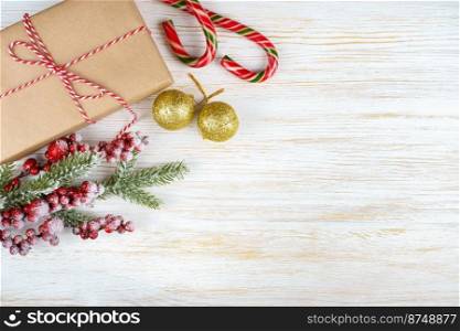 New year background with christmas tree branch, candy, golden balls and gift box on white wooden background with copy space. Christmas background with decorations and gift box on white wooden background.