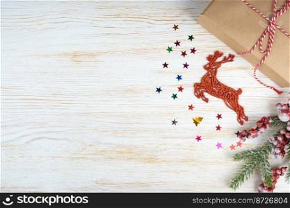 New year background with christmas tree branch, decorative deer and gift box on white wooden background with space for text. Flat lay, top view.. Christmas background with decorations and gift box on white wooden board