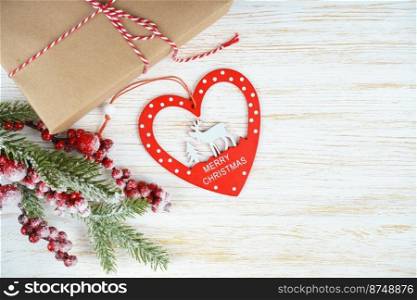 New year background with christmas tree branch, decorative heart with a deer and gift box on white wooden background with copy space. Flat lay, top view.. Christmas background with decorations and gift box on white wooden board