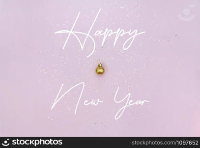 New Year celebration concept. Golden Christmas ball, lettering and golden star sequins on pastel pink background. Template for invitation or greeting card.. New Year celebration concept. Golden Christmas ball, lettering and golden star sequins on pastel pink background.