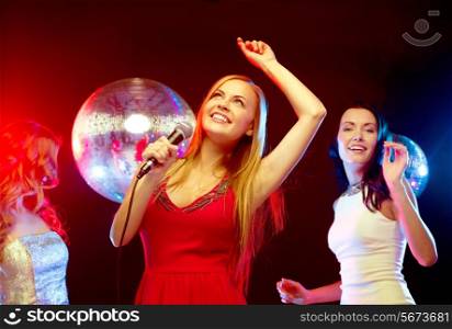 new year, celebration, friends, bachelorette party, birthday concept - three women in evening dresses dancing and singing karaoke