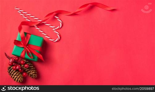 New Year Christmas holiday presents. Flat lay top view of gift box, pine cones and candy Xmas decoration on red background with copy space for text, Happy new year day concept