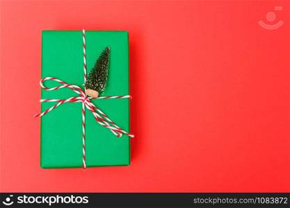 New Year, Christmas Xmas holiday composition, Top view gift green box, clews of rope and green fir tree branch on red background with copy space