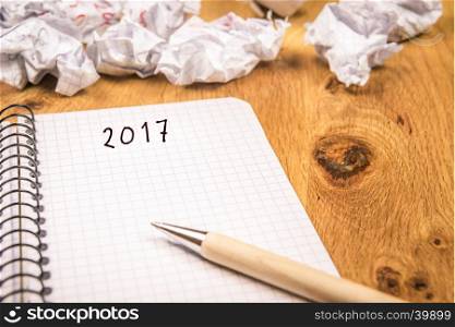 New year concept with 2017 written on a graph, spiral notebook and crumpled pages in the background suggesting the passing of years.