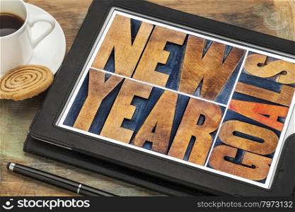 New Year goals - word abstract in vintage letterpress wood type on a digital tablet with a cup of coffee