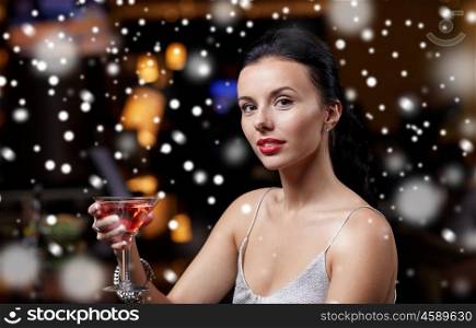 new year party, christmas, winter holidays and people concept - glamorous woman with cocktail at night club or bar over snow