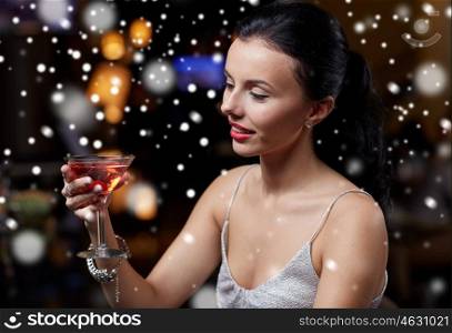 new year party, christmas, winter holidays and people concept - glamorous woman with cocktail at night club or bar over snow