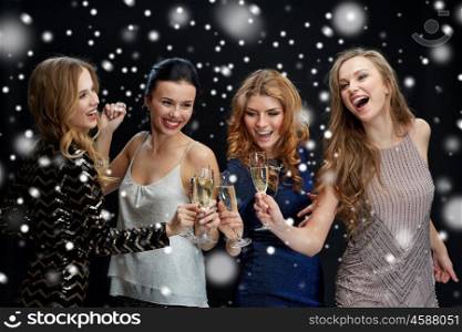 new year party, christmas, winter holidays and people concept - happy women clinking champagne glasses and dancing over black background with snow